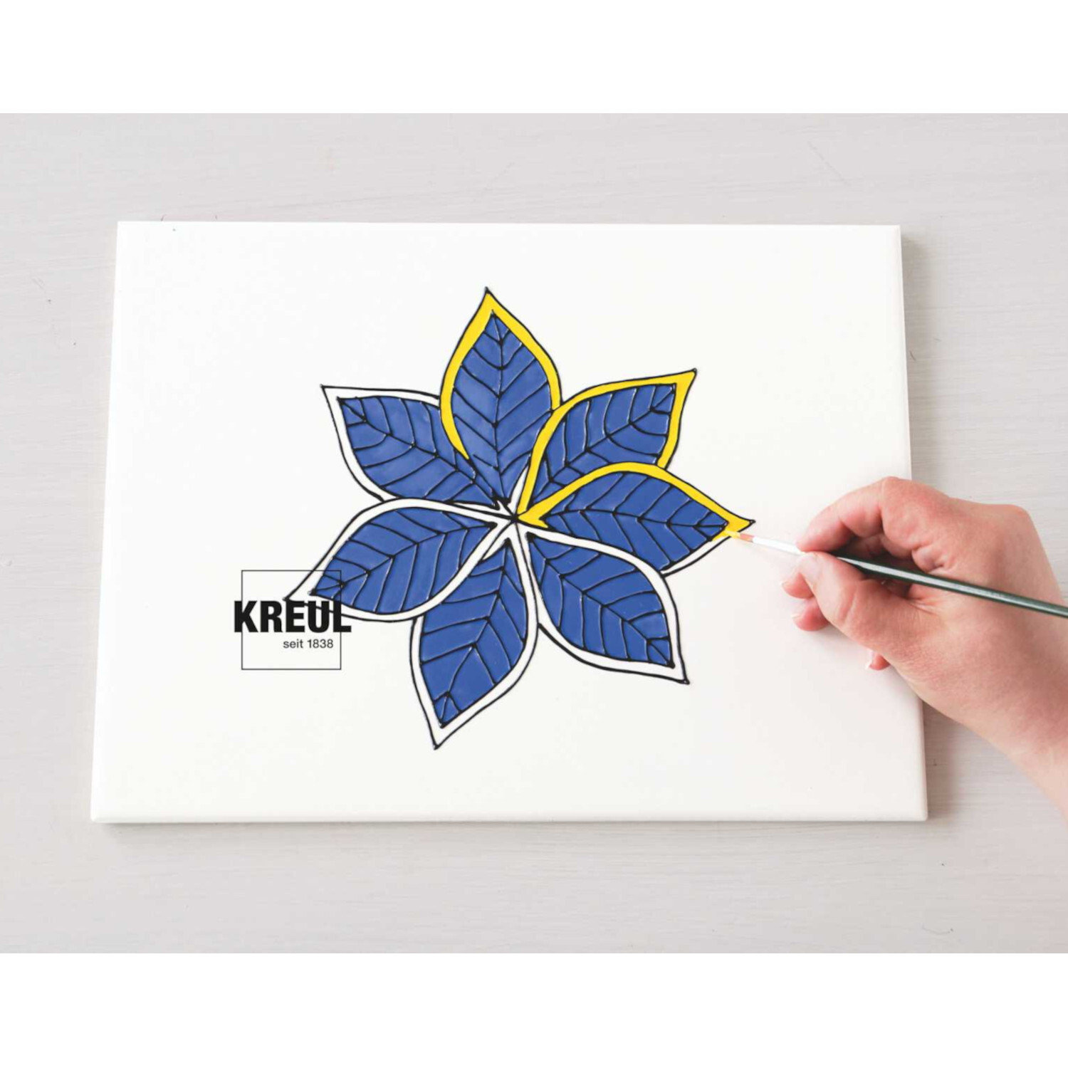 Graphit-Kopierpapier A4 10Blatt: Hand malt blaue Blume auf Leinwand, KREUL-Logo sichtbar.