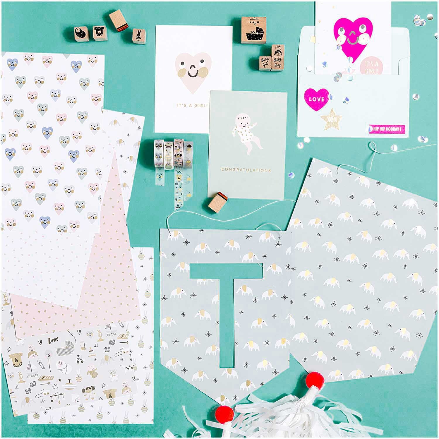 Paper Poetry Tape Hello Baby Rasselhase von Rico Design, umgeben von niedlichen Baby-Motiven und Bastelmaterialien auf einem türkisfarbenen Hintergrund.